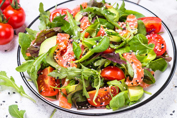 Salmon salad with fresh vegetables on white.