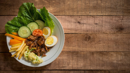 Asian style satay beef with mixture of vegetables in bowl on wooden table - rustic style food concept flat lay image with copy space for text.