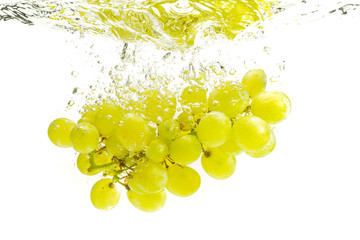 Bunch of green grapes sinking into crystal clear water.