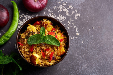 vegetarian paneer biryani at black background. paneer biryani is traditional veg indian cuisine dish with paneer cheese, basmati rice, masala, chili pepper, mint and many another spices. Copy space