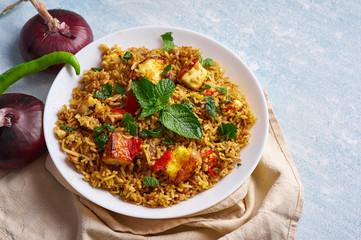 vegetarian paneer biryani at blue background. paneer biryani is traditional veg indian cuisine dish with paneer, basmati rice, masala, chili, mint. Copy space