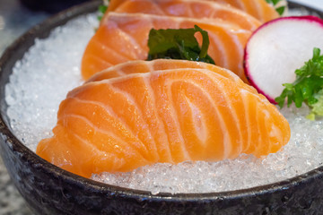 salmon sashimi on ice in black bowl japanese food