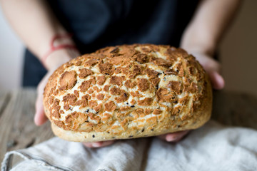 Woman holding freshly baked sourdough bread loaf