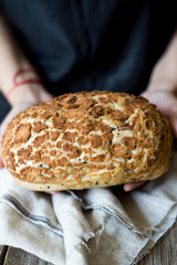 Woman holding freshly baked sourdough bread loaf