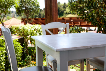 White table with chairs on the beauitiful sunny graden view. Terrace with garden landscape. 