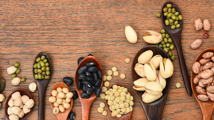 Obraz na płótnie Canvas Assortment of beans and lentils in wooden spoon on teak wood background