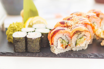 Sushi and sushi roll set on black stone table.