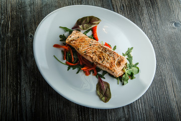top view of baked salmon fillet with green salad and arugula