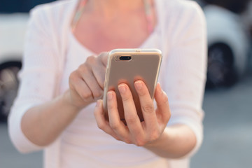 Close view of a young person holding and making use of a mobile phone or smart phone. Blurred background