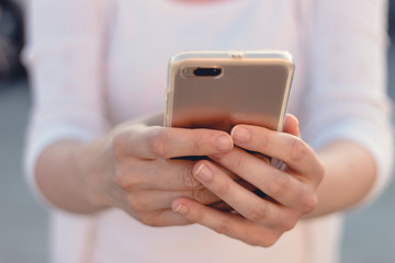 Close view of a young person holding and making use of a mobile phone or smart phone. Blurred background