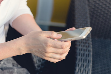 Close view of a young person holding and making use of a mobile phone or smart phone. Blurred background