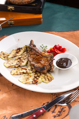 Pork Brisket with grilled zucchini and chili pepper on white plate on old map background