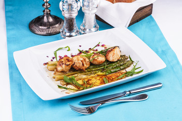  European recipe, Mediterranean dish. Caramelized asparagus with onion chips, rose petals, arugula and pieces of fried fish