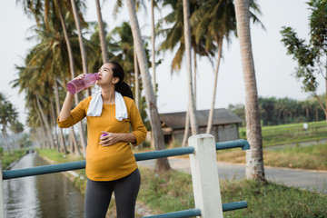 thirsty pregnant woman after workout drinking a bottle of water