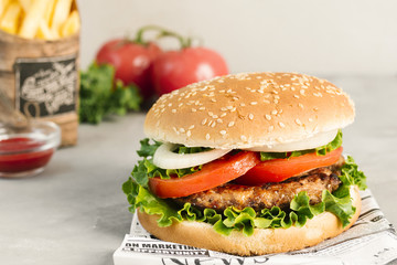 High angle close-up of burger and fries on newspaper