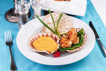 European recipe, Mediterranean dish. Baked mollusk in the oven under a cheese cap, served with crispy fish slices and greens, onions and red pepper according to a national recipe