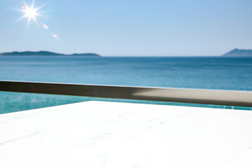 A white table background on a balcony  on a beautiful sunny blue sky and ocean view,
