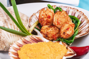 European recipe, Mediterranean dish. Baked mollusk in the oven under a cheese cap, served with crispy fish slices and greens, onions and red pepper according to a national recipe