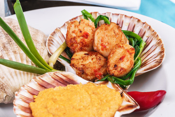 European recipe, Mediterranean dish. Baked mollusk in the oven under a cheese cap, served with crispy fish slices and greens, onions and red pepper according to a national recipe
