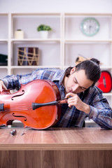Young handsome repairman repairing cello