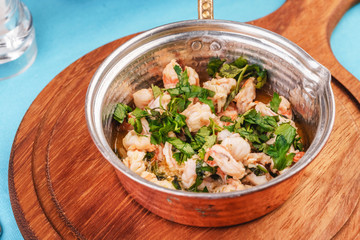 roast in a frying pan with greens, fish meat and shrimp according to an Italian recipe