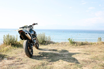 Obraz premium A motorcycle on the sandy cliff on the blue sky and ocean view in distance.