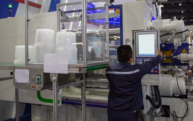 Industrial technician operate plastic injection molding press machine in manufacturing factory