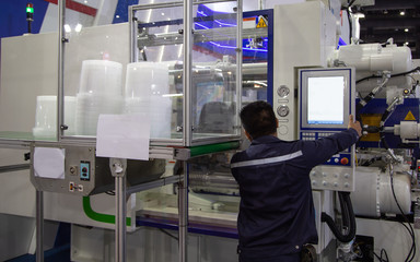 Industrial technician operate plastic injection molding press machine in manufacturing factory