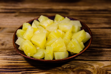 Ceramic plate with chopped canned pineapple on wooden table