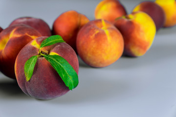 Ripe peaches with leaves on white background