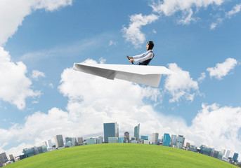 Aviator driving paper plane above business center