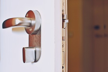 Close up of an open door with a metallic secure lock doorknob. 