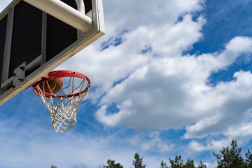 Basketball backboard with a ring on the street and blue sky
