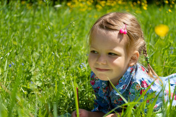 Portrait of a girl of 4 years on a green lawn. Girl on the grass in the park