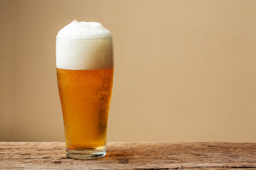 Glass beer on wooden table with cream wall background. copy space for design.