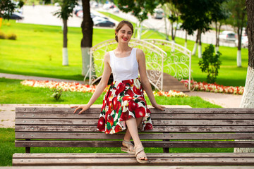 Naklejka premium Beautiful girl in summer dress sitting on a park bench