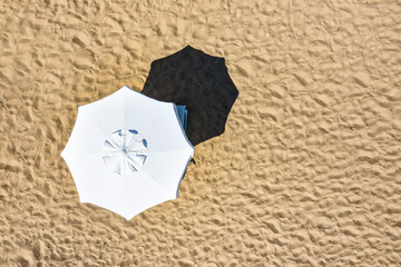 Summer umbrellas and sun beds on sandy beach. Sunbathing, relaxing and lying on the beach.
