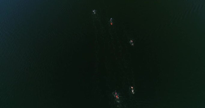 Drone shot of athlets swimming in the dark sea. People wearing swimmwear in the lake. Top view from drone. Swimmers in the water.