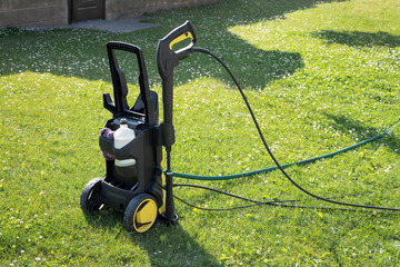 mini home pressure washer for cleaning the car on the background of green lawn