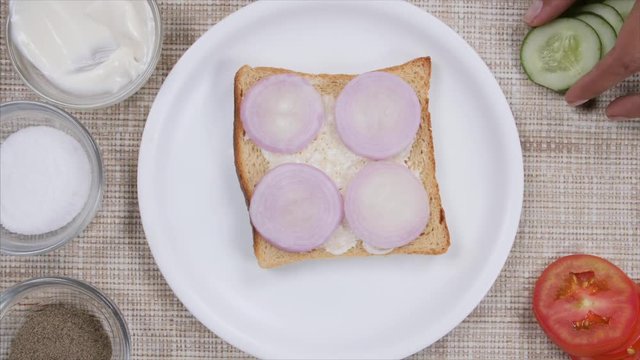 A girl under the process of making a healthy vegetable sandwich. 