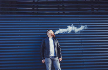 Bearded man exhales cloud of smoke on blue background