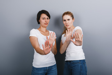 Two women showing  a gesture of repel and looking at the camera.- Image