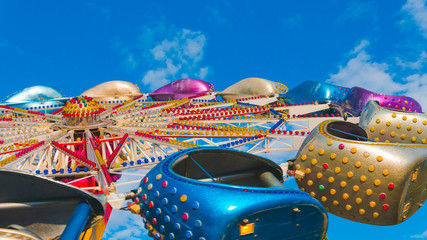 The carousel in amusement park, close-up. The Carousel is spinning against the blue sky