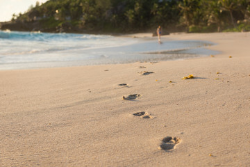 Human deep barefoot footprints and woman far