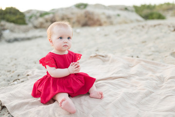 Beautiful little girl sitting on the beach