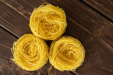 Group of three whole raw pasta angel hair flatlay on brown wood