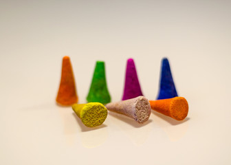 Multicolored aromatic cones for incense stand on a white surface. Partially scattered on the table