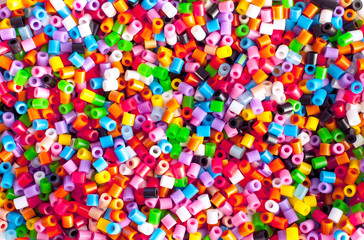 Fototapeta na wymiar Bright colorful plastic perler beads. Abstract background