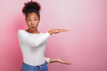 Surprised young woman showing copy space gesture from both arms by side from herself