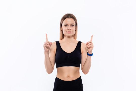 Young sporty blond woman in a black sportswear with smart watches for pulse measuring pointing with fingers up.